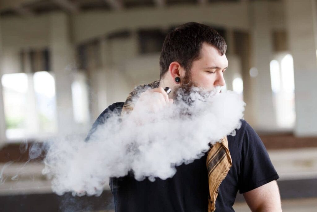 A guy vaping a 3chi disposable in a parking lot A guy vaping a 3chi disposable in a parking lot