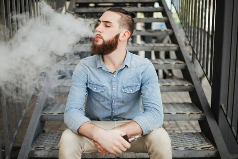 A guy vaping outdoors to deal with his anxiety issues