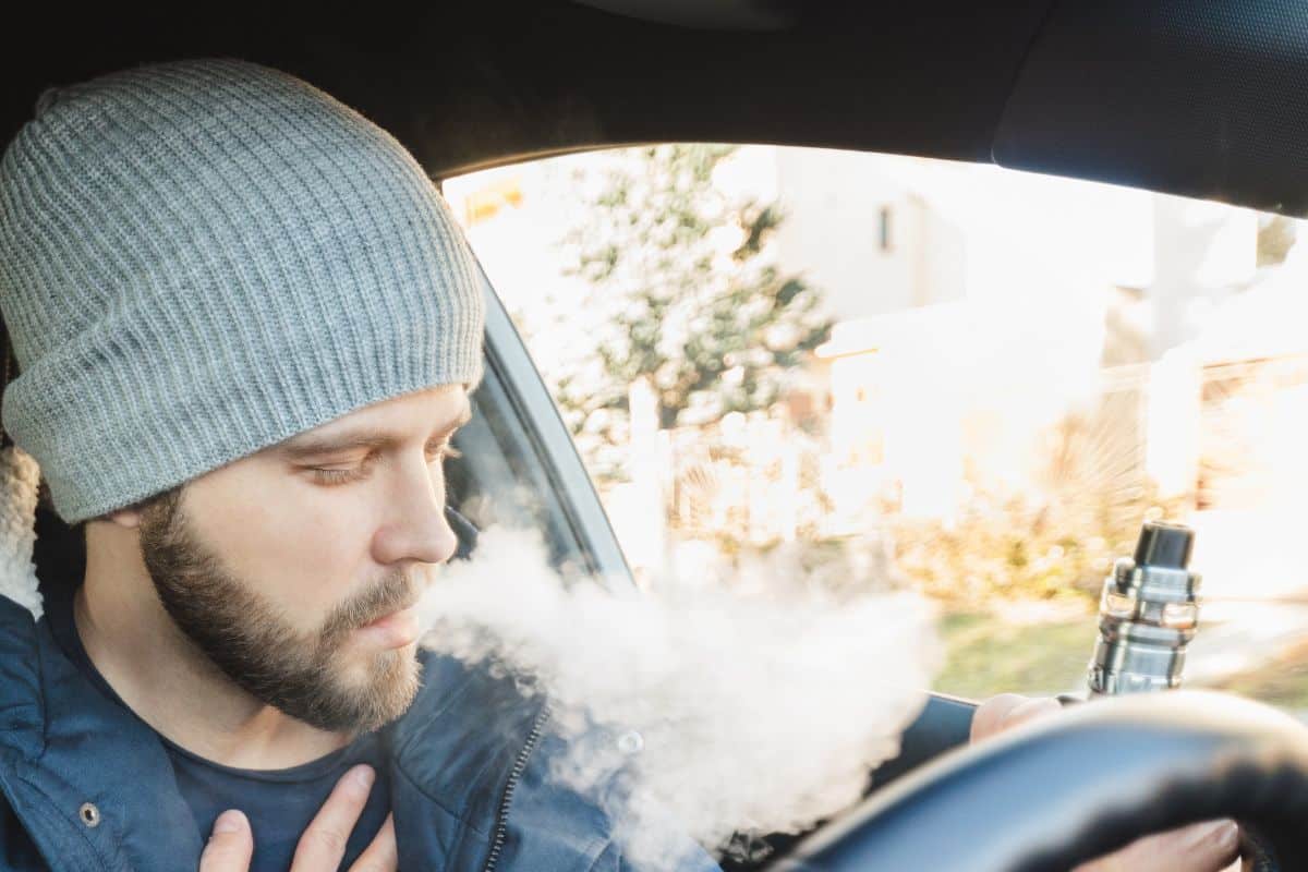 A guy enjoying vaping inside a car