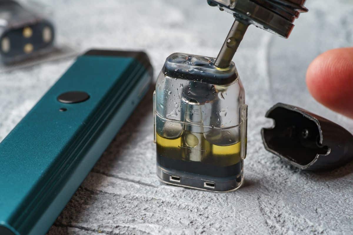Refilling an electronic cigarette pod with vape juice, ensuring it does not get out of clothes.