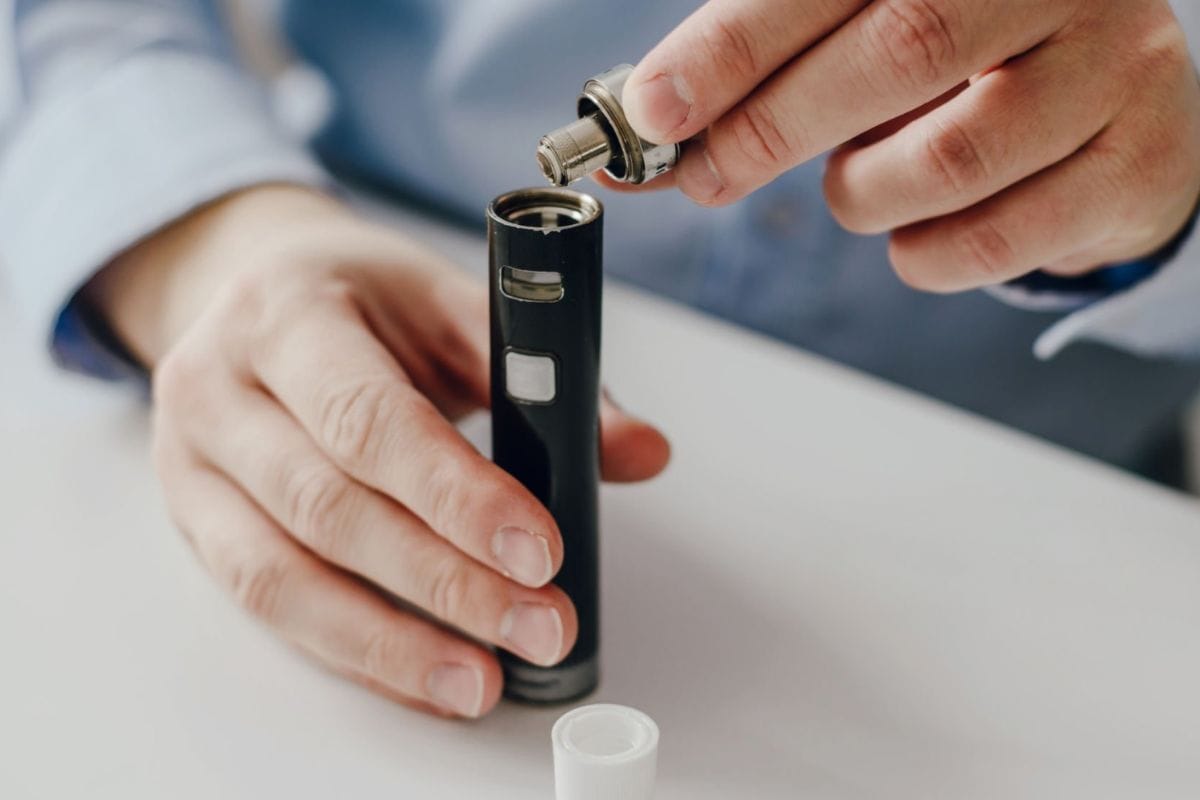A person swapping out the vape cartridge from a vape device